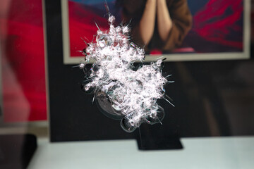 shattered glass surface with a prominent starburst impact, featuring a blurred background.