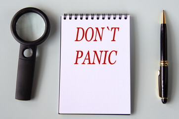 DON'T PANIC - the words are in a black notebook with a magnifying glass and pen in the background.