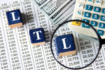 LTL - acronym on wooden cubes against the background of banknotes and calculator
