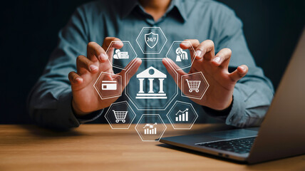 Hands in gray sleeves present a hexagonal holographic banking interface above a laptop with dark, moody lighting and cool blue background tones