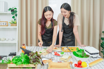 Two asian woman study online in the classroom making sandwich together in the home kitchen. Homemade and Learn online concept	