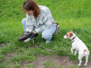 A woman cleans up dog excrement while on a walk.