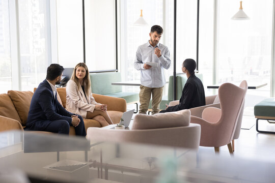 Group discussion and training. Diverse multicultural corporate employees managers clerks meet together in coworking space answer young man trainer team leader questions discuss idea in casual workshop