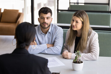 Seeking advice. Attentive family couple clients of bank manager real estate agent broker discuss...