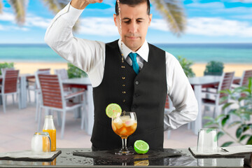 Cropped shot of a barman making a orange cocktail at beach hotel.