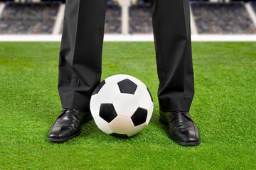 Cropped shot of a black shoes of businessman with suit standing at soccer field with ball classic