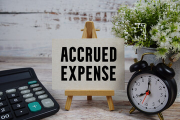 Accrued Expense text with alarm clock and calculator on wooden background