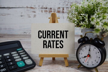 Current Rates text with alarm clock and calculator on wooden background