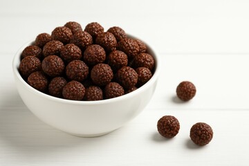 Delicious chocolate-coated puffed rice treats in a bowl on a wooden surface, close-up shot.