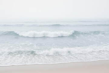Aerial perspective of surf pounding the shoreline amidst thick fog