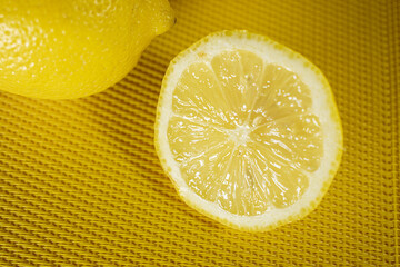 Halved lemon on a textured yellow surface, highlighting juicy segments and seeds. Bright, fresh,...