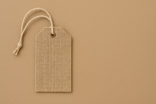 Rustic fabric luggage identifier with string attachment on neutral paper background