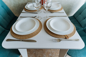 A beautifully arranged table is set with an array of plates, utensils, and elegant wine glasses...