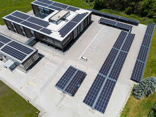 Aerial view of building with solar panels on a roof and parking space with solar canopies