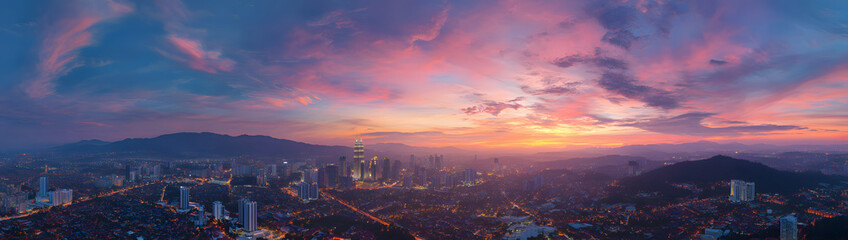Fototapeta premium Aerial View of City Skyline at Sunset with Colorful Clouds