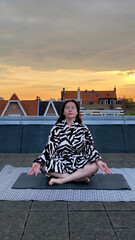 Overweight woman morning exercises old Dutch house body positive pink sunrise Netherlands yoga