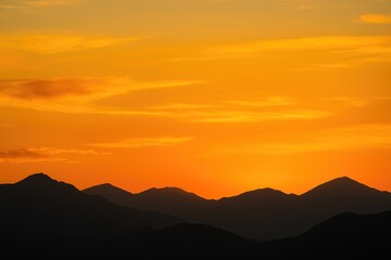 Fototapeta premium Golden sunset sky above shadowy mountain range