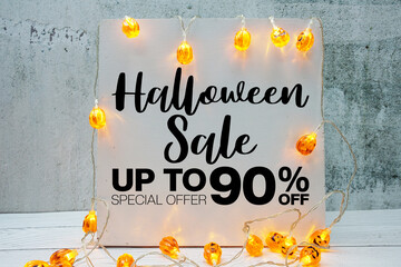 Halloween Sale 90% off text with LED pumpkin decoration on wooden background