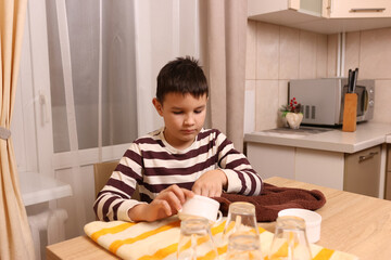 Boy wipes glasses and cups with a towel. Housework.