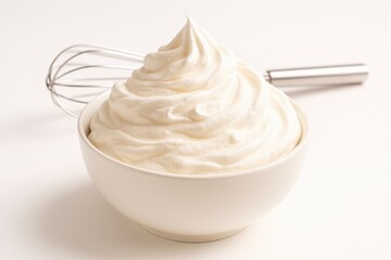 Cream being whipped with a whisk on a plain white surface