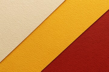 Close-up of textured craft paper featuring white, yellow, and red hues with a vintage geometric cardboard design and gradient effects, set against a felt background.