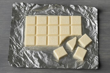 Crushed white or coconut chocolate bar wrapped in foil on a grey wooden surface with distinctive sweet and unusual flavor profiles