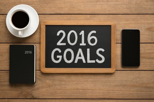 Goals for 2016 displayed on a blackboard alongside coffee, a mobile phone, and a notebook