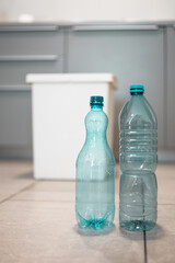 Plastic bottles next to a trash bin. Sorting plastic for easier recycling of waste.
