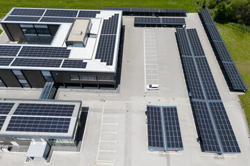 Aerial view of building with solar panels on a roof and parking space with solar canopies