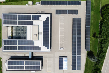 Aerial view of building with solar panels on a roof and parking space with solar canopies