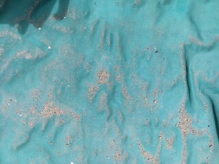 Worn Dusty Blue Tarp Surface with Wrinkles and Sand. Close-up of a weathered blue-green tarp covered with dust, sand, and wrinkles. Natural texture from prolonged outdoor exposure