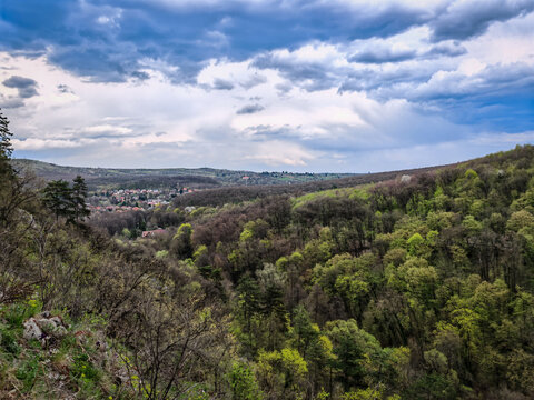 View of the forested Moln&aacute;r Rock formation in spring with the city of Miskolc visible in the background. Located in the B&uuml;kk Mountains near Lillaf&uuml;red.