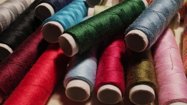 Close-up of colorful sewing thread spools highlighting vibrant textures and rich fabrics in a creative workspace