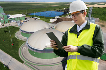 Engineer with digital tablet on a background of biogas plant