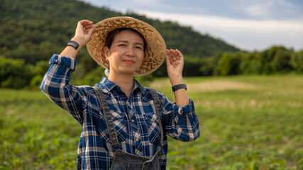 Smiling Woman Adjusts Hat in Green Farm Landscape