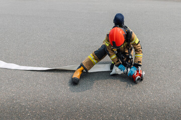 Firefighter Preparing Fire Hose on Asphalt During Emergency Drill