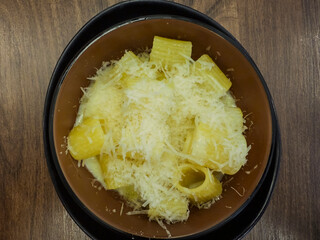 Delicious paccheri pasta with grated cheese in brown bowl