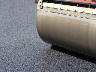 Road roller lays new asphalt. Highway construction. Road roller fragment. Asphalt paver at work....