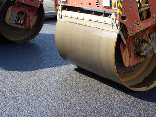 Road roller on asphalt pavement. Several asphalt pavers nearby. Road roller on asphalt pavement...