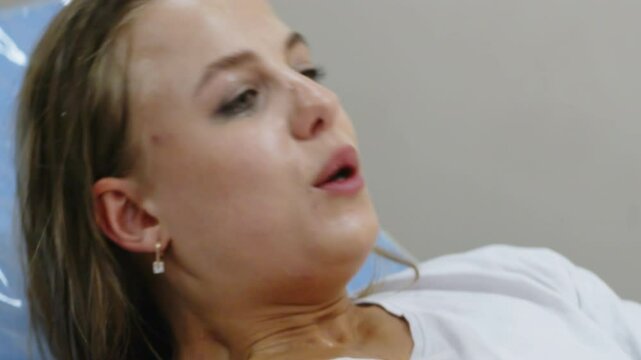 In a delivery room, a young woman is pushing during labor, face tense. Concept of birth effort and the strength of the female body.
