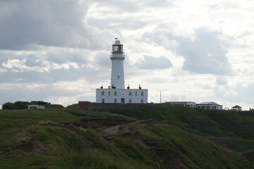 A white lighthouse standing tall on a coastal clifftop overlooking the North Sea in Flamborough,...