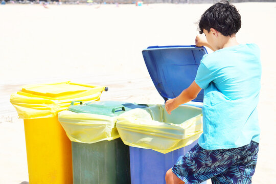 teenage boy throwing garbage in the appropriate recycling garbage can at the beach during summer vacation - Powered by Adobe