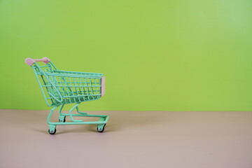 Mini Trolley shopping cart with space for text on pink and green background