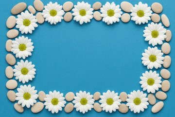 Obraz premium Design featuring a pebble and floral border on a blue background with space for text from a top view perspective