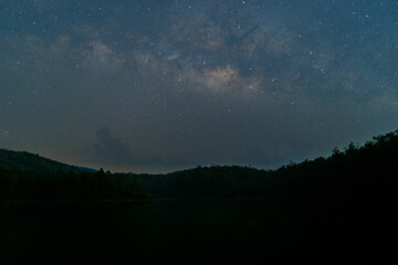Landscape with Milky Way. Night sky with stars and silhouette of a standing happy man on the mountain at asia Thailand
