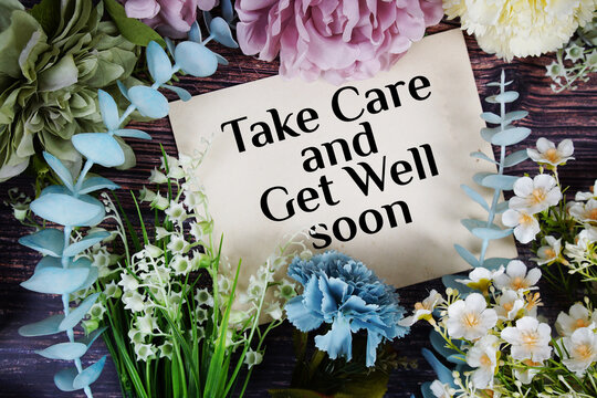 Take care and get well soon text with flowers bouquet decoration on wooden background