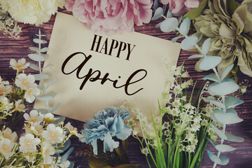 Happy April text with flowers bouquet decoration on wooden background