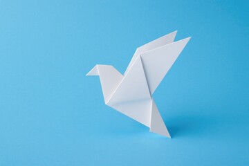 Blue background with a white folded paper bird symbolizing peace