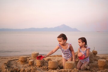 Sisters building sandcastles at sunset on a tranquil beach
