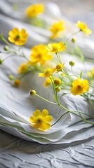Delicate yellow buttercups rest on soft white fabric